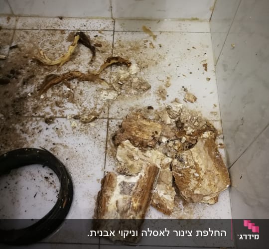חלקי צינור שבור ופסולת על רצפת חדר אמבטיה